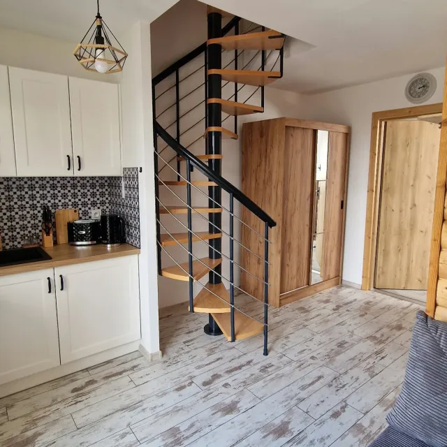 Biała kuchnia z drewnianym blatem i spiralnymi schodami w apartamencie Białym