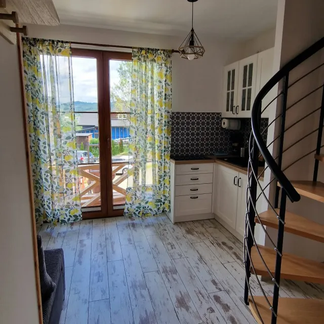 Salon z wyjściem na balkon i schodami na poddasze w apartamencie Białym