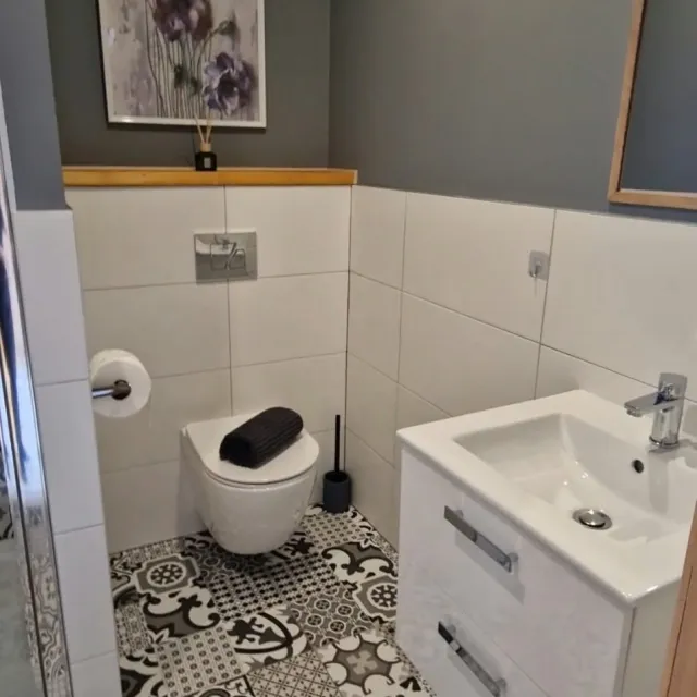 Łazienka z umywalką i toaletą na czarno-białych kafelkach w apartamencie Białym
