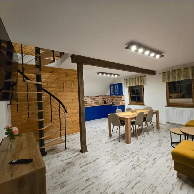 Salon z telewizorem, spiralnymi schodami i jadalnią w apartamencie Niebieskim