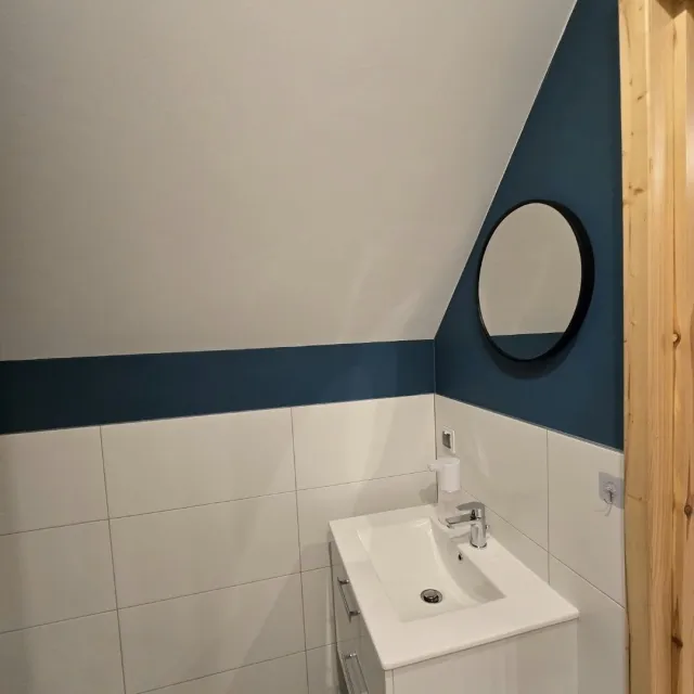 Łazienka z okrągłym lustrem i umywalką w apartamencie Niebieskim