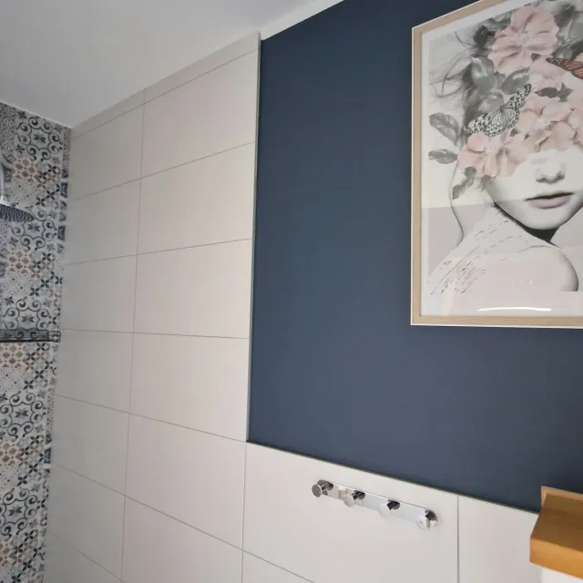 Prysznic z wzorzystymi kafelkami i granatową ścianą w apartamencie Szarym
