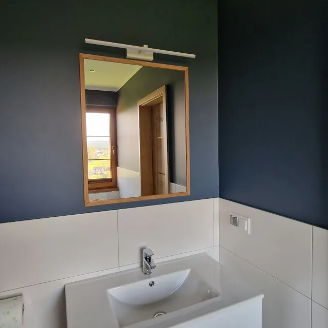 Umywalka z lustrem w granatowej łazience apartamentu Szarego